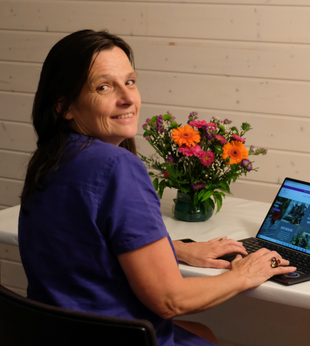 femme assise qui nous regarde en tapant sur son pc